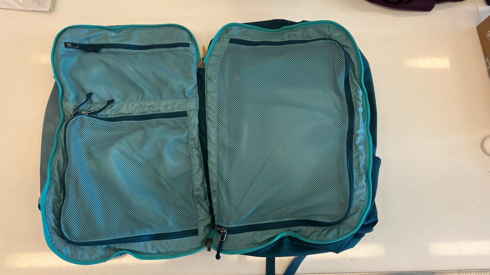 an open cotopaxi allpa 42l pack on a white table, good housekeeping's testing for the best carry on backpacks