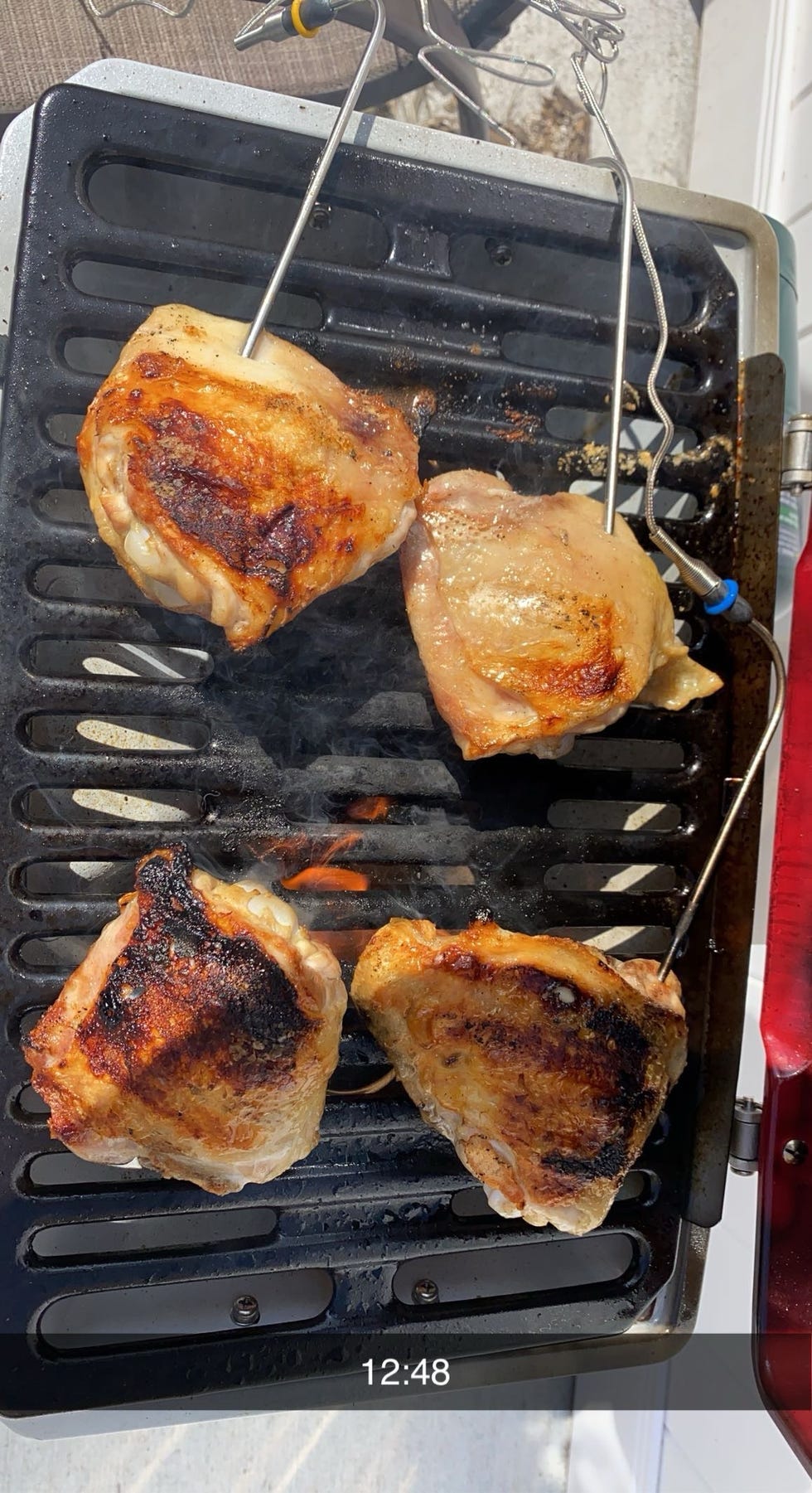 chicken thighs on a grill with thermometers inserted