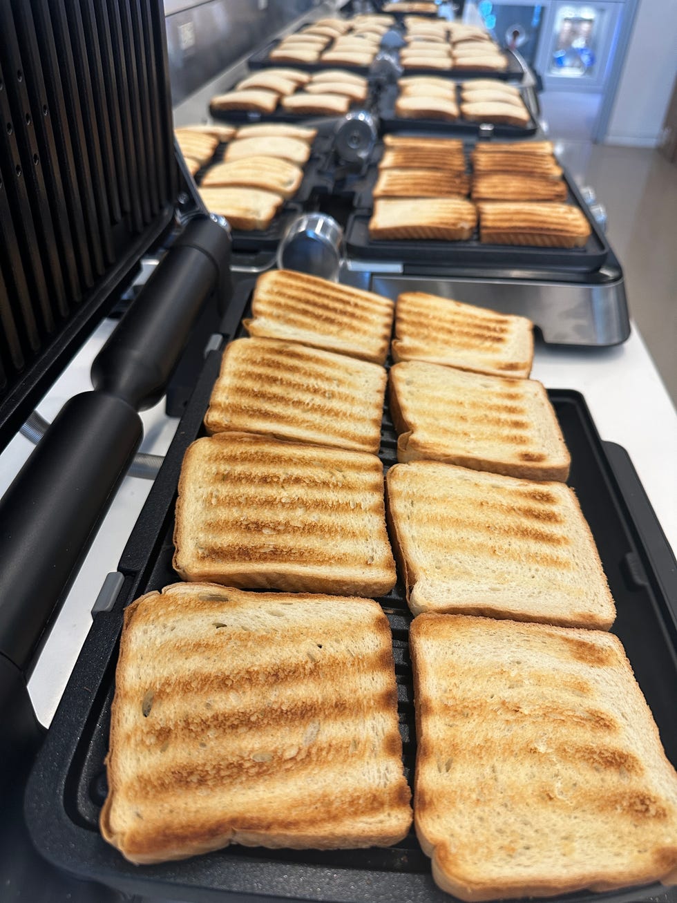 a row of panini presses with toasted bread slices