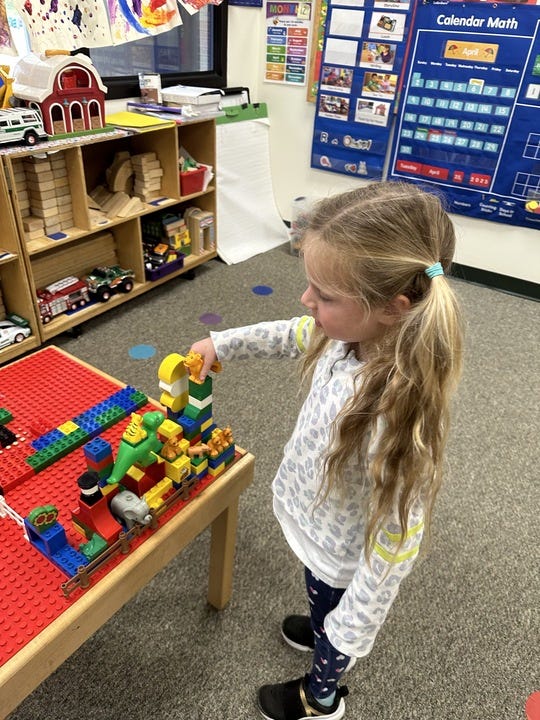 girl with blonde ponytails builds legos with the help of a raised lego table, part of the good housekeeping tests for the best lego tables