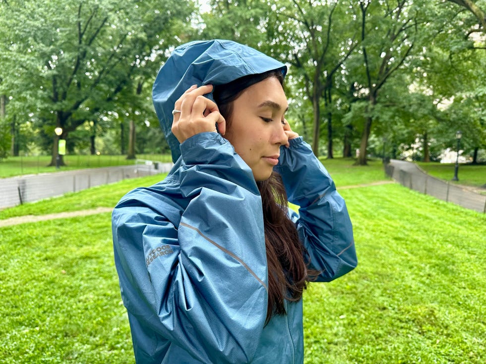 woman modeling a blue raincoat in a park