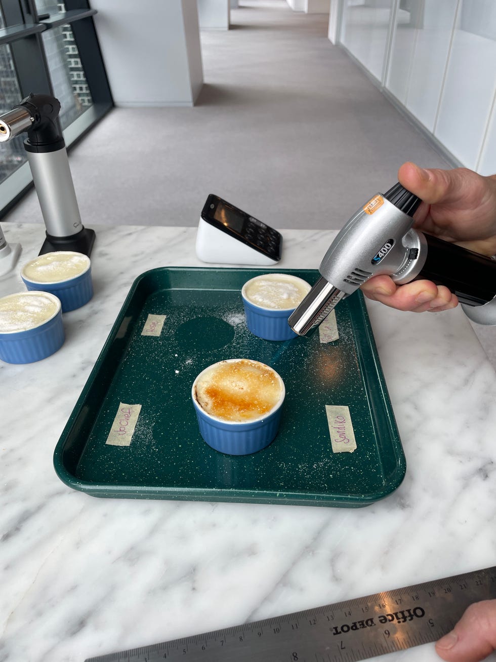torching small pots of creme brulee with a kitchen torch
