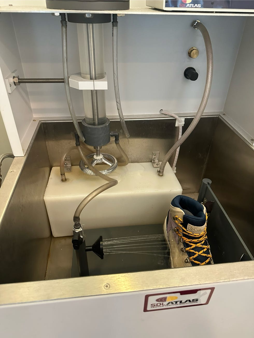 a hiking boot is placed in a rain tester and sprayed