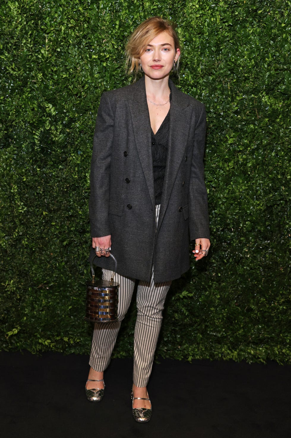 imogen poots stands in front of a living bush wall at a red carpet event