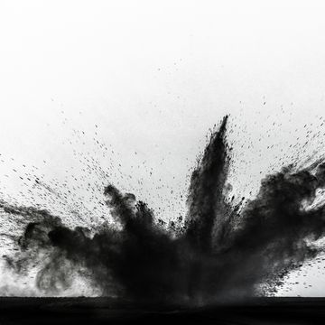 impact and explosion of black dust and smoke particles on a white background