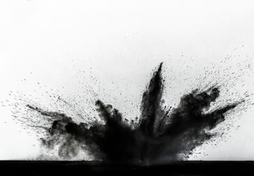 impact and explosion of black dust and smoke particles on a white background