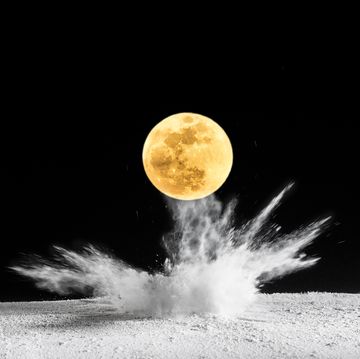 impact of full moon super moon on the soil, producing an explosion and a crater of powder on a black background spain
