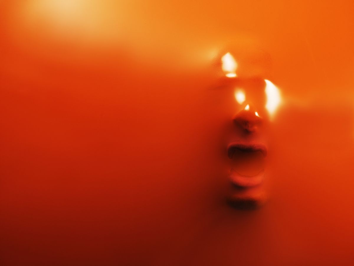 impression of man's face through orange rubber, close up