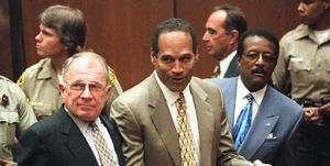 f lee bailey stands and looks left, oj simpson holds his fists in front of him and looks left, johnnie cochran stands and looks left, all three men wear suits with ties