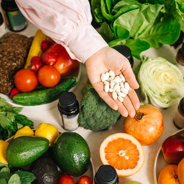 in the dietitian's office, the table is set with vegetables, fruits, nuts, bread, herbs, capsules of drugs in the palm