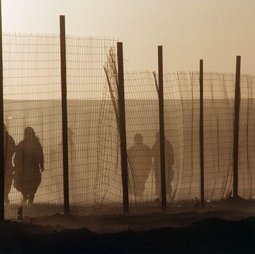 sahrawivrouwen lopen langs het hek van het algerijnse vluchtelingenkamp smara
