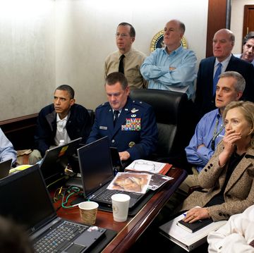 president obama and his advisers sitting around a table with computers and documents on it