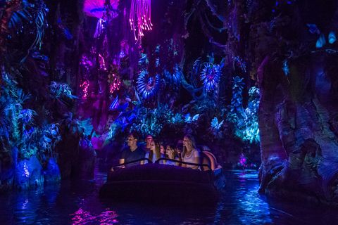 pandora world of avatar ride, family sitting in ride as it cruises down a river with neon lights all around the rainforest