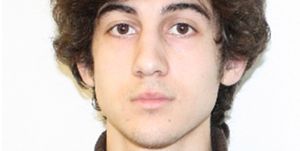 dzhokhar tsarnaev looks straight at the camera with a neutral expression on his face, he wears a brown sweater