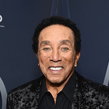 smokey robinson smiles wearing black suit