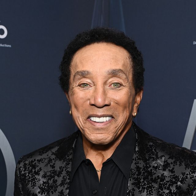 smokey robinson smiles wearing black suit