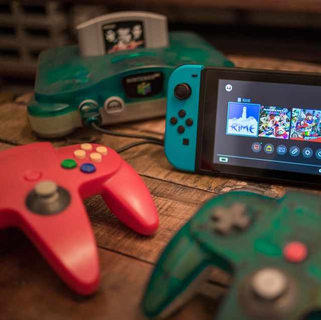 a vintage n64 console pictured with multiple controllers and a nintendo switch