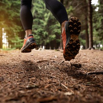 in winter running sports shoe, woman running in the forest