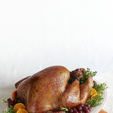 golden roasted turkey on a serving platter with grapes, orange slices, and herbs