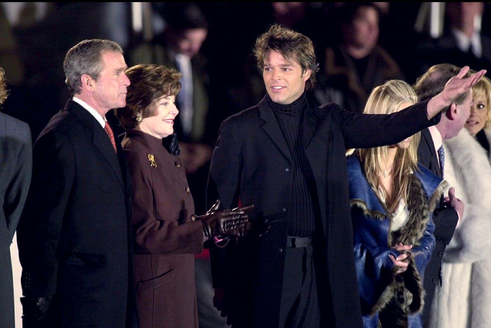 ricky martin extending his arm as he speaks to president george w bush and laura bush