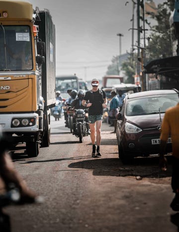 a person running on a busy street in india amidst vehicles