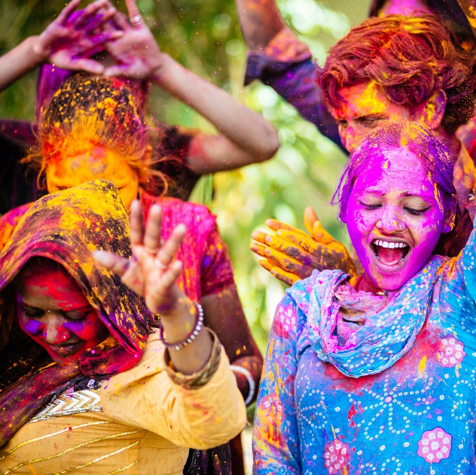 indian friends dancing covered on holi colorful powder in india