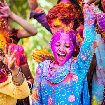 indian friends dancing covered on holi colorful powder in india