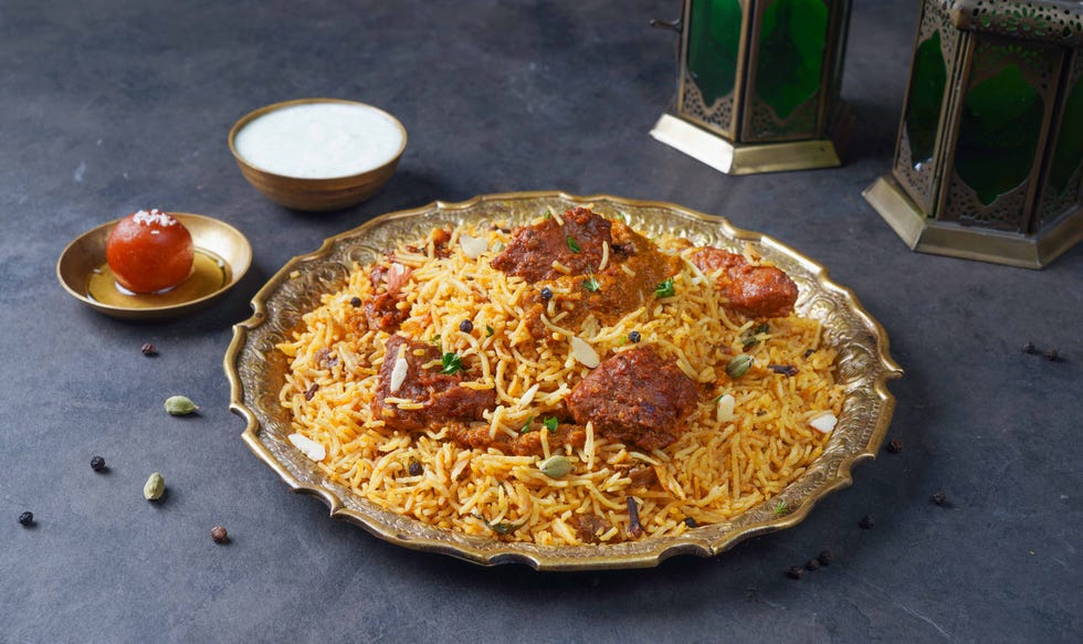 indian spicy beef biryani with raita and gulab jamun served in a dish side view on grey background