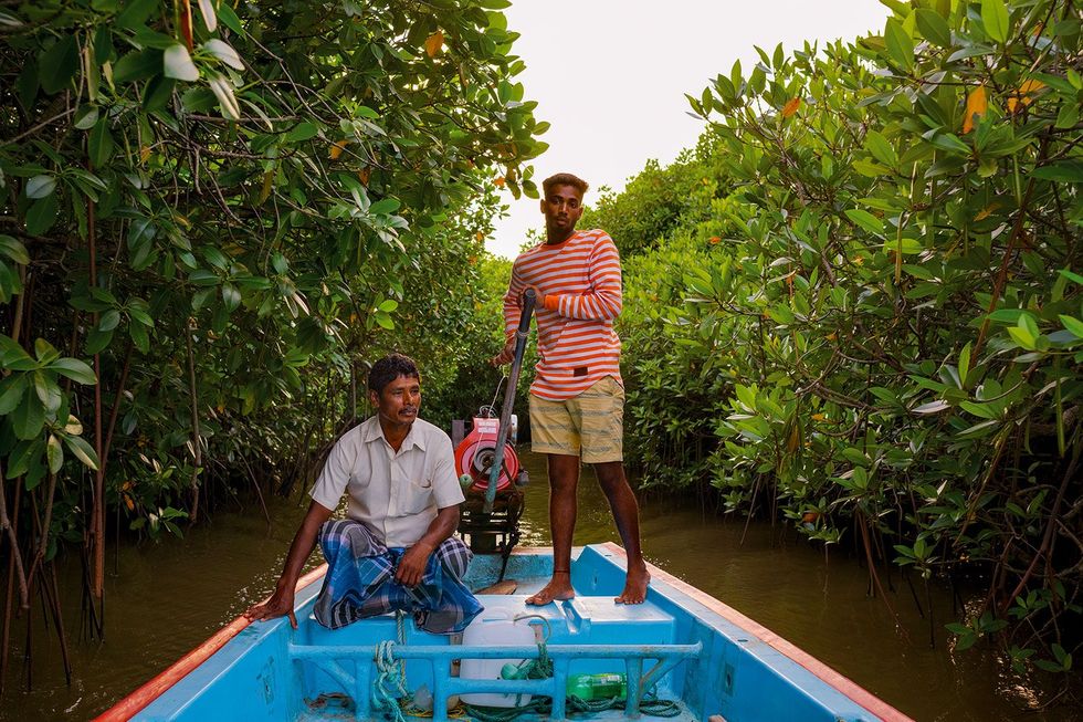 Rakesh Kumar staand en zijn vader Selvadurai werken als visser in de deelstaat Tamil Nadu in het zuiden van India Ze varen door de Pichavaram het op een na grootste mangrovebos ter wereld De bomen slaan een bescheiden hoeveelheid CO2 op in de bodem maar door klimaatverandering valt er minder regen en stijgt de temperatuur waardoor er op termijn wellicht minder CO2 wordt vastgehouden