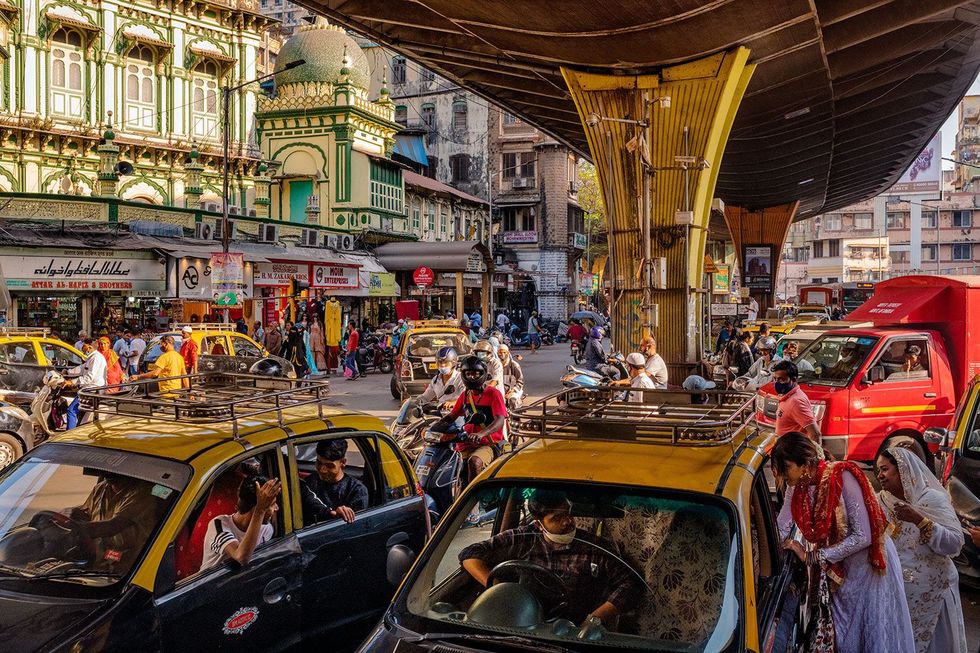 Voetgangers motoren en taxis bepalen het straatbeeld in Mumbai een agglomeratie waar zon 21 miljoen mensen wonen India is hard op weg om China in te halen als het land met de meeste inwoners Die groei brengt uitdagingen met zich mee vooral in het terugdringen van de broeikasgasuitstoot