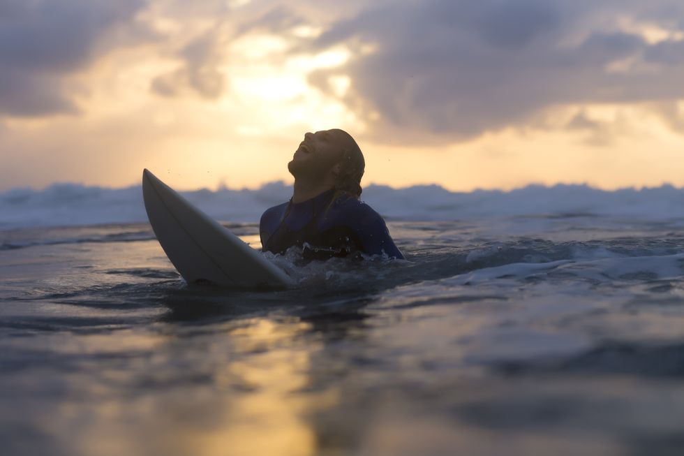 indonesia, bali, surfer in the ocean at sunrise