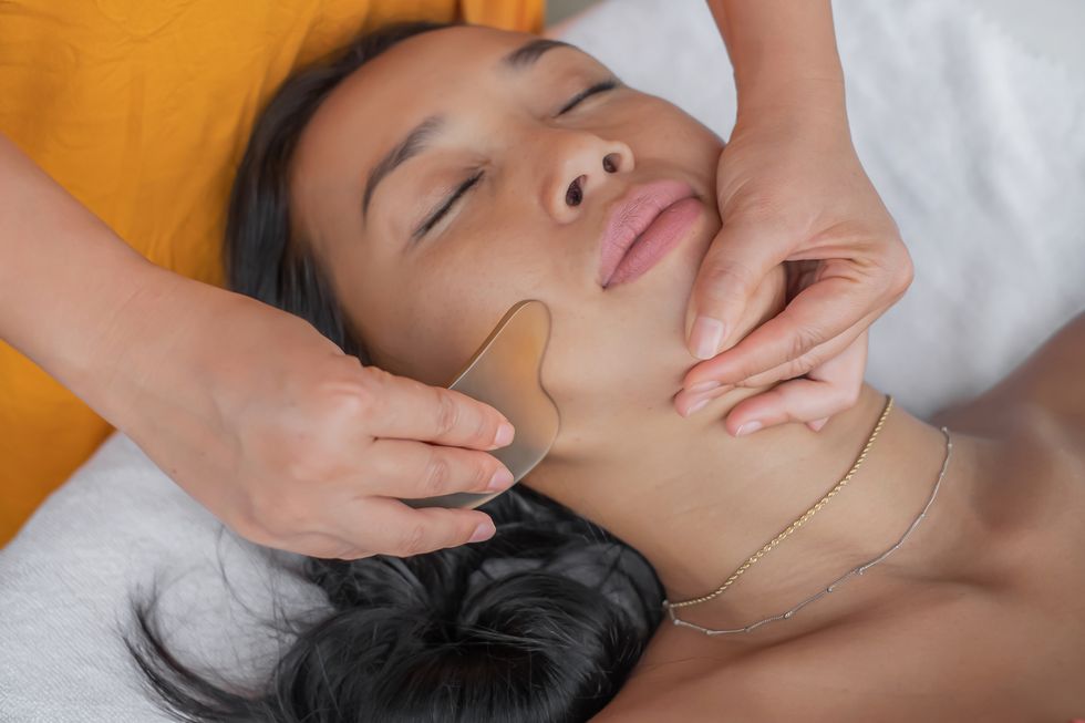 indonesian woman having facial gua sha in a health spa