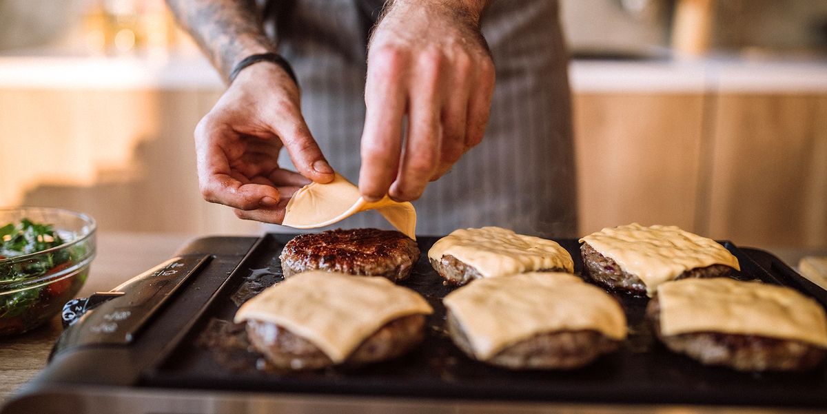 man putting cheese on burgers on indoor grill