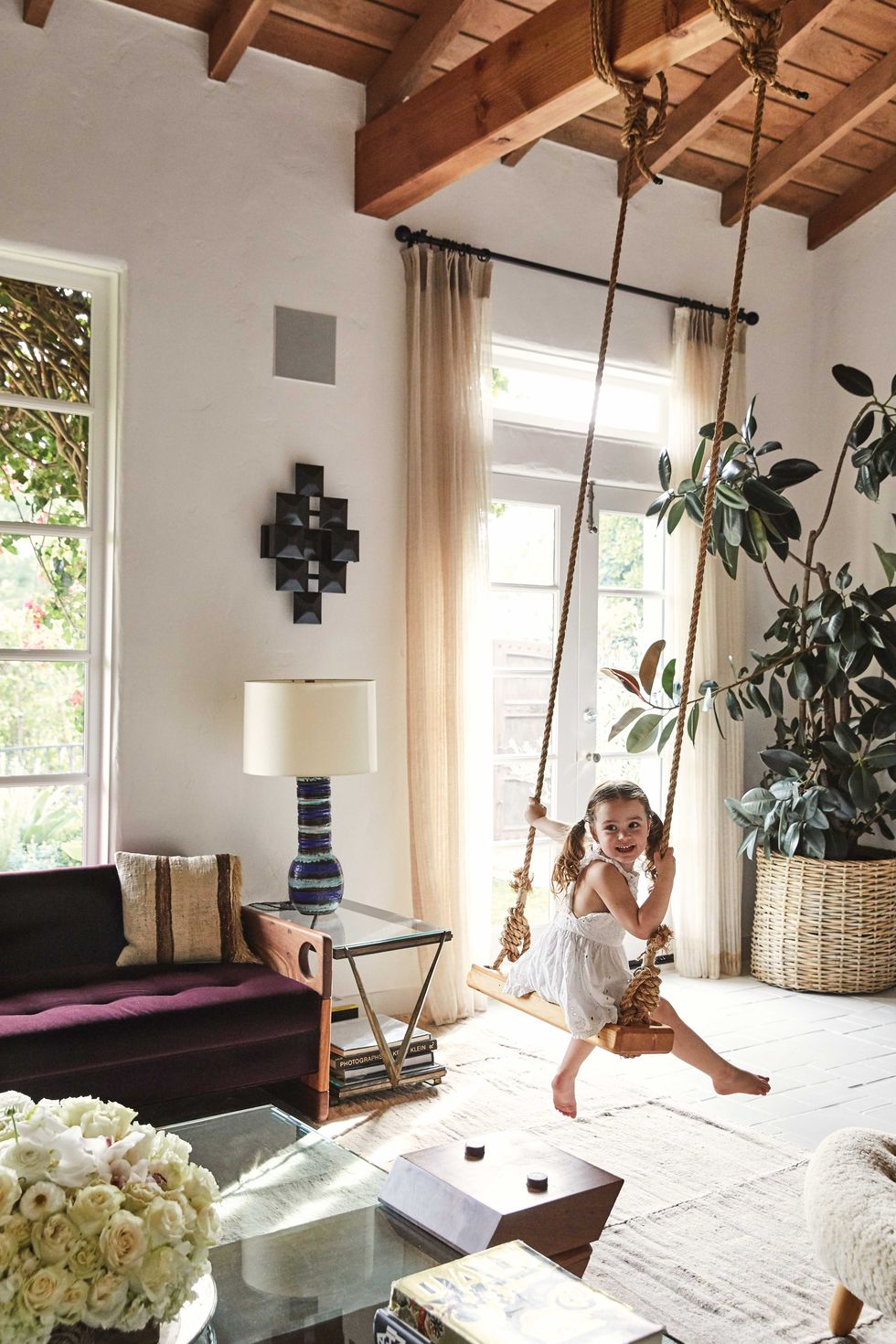 a young girl swings on an indoor swing in a formal living room