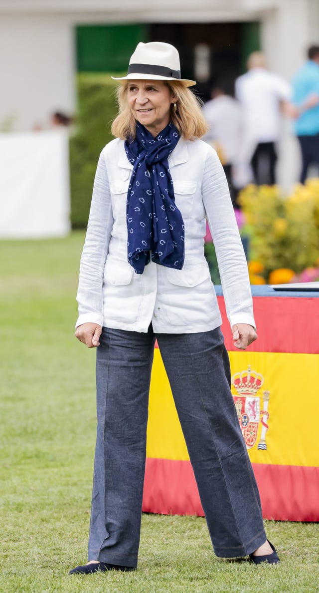 la infanta elena con sombrero, una blazer blanca y panuelo azul al cuello