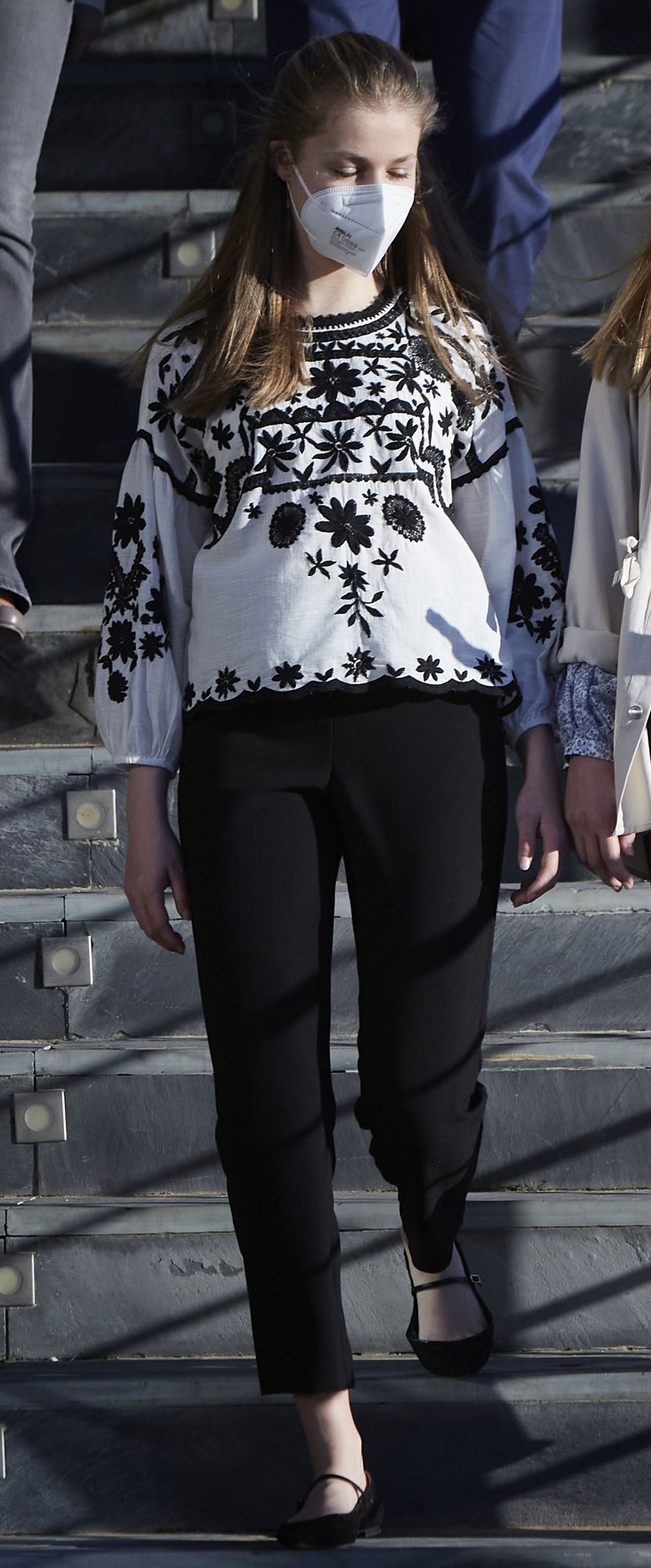 la infanta sofia con lusa de base blanca con bordados florales en negro de la firma española de moda sfera y pantalones negros en la visita al centro de refugiados ucranianos de madrid
