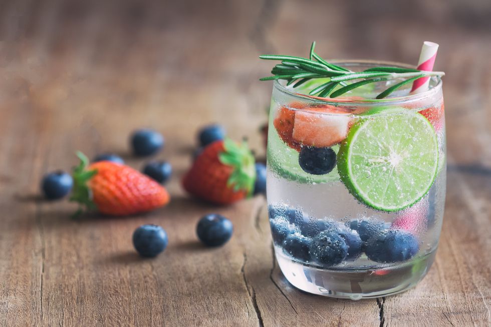 Infused water made from blueberry strawberry and lemon in sparkling mineral water look so freshness and healthy. Mixed fruit mojito on wood table with copy space. Summer refreshing drink concept.