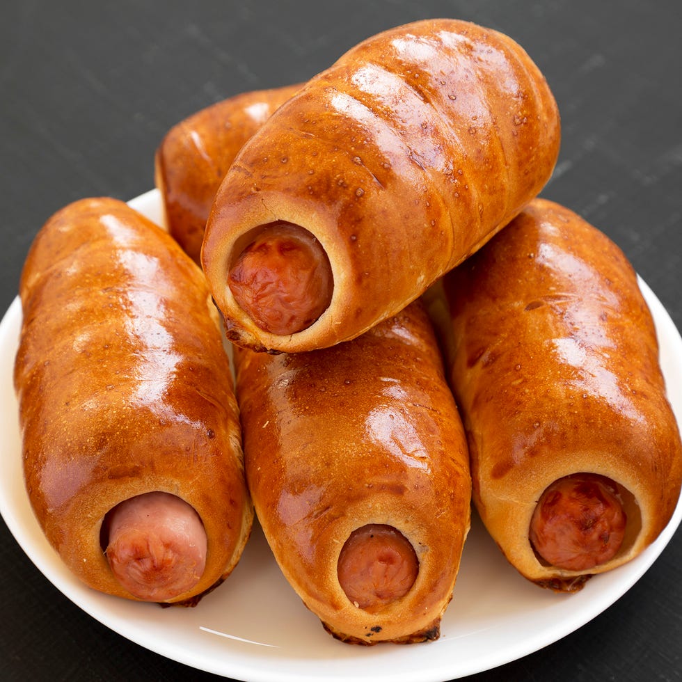 homemade beef sausage kolache on a white plate on a black surface, side view. close up.