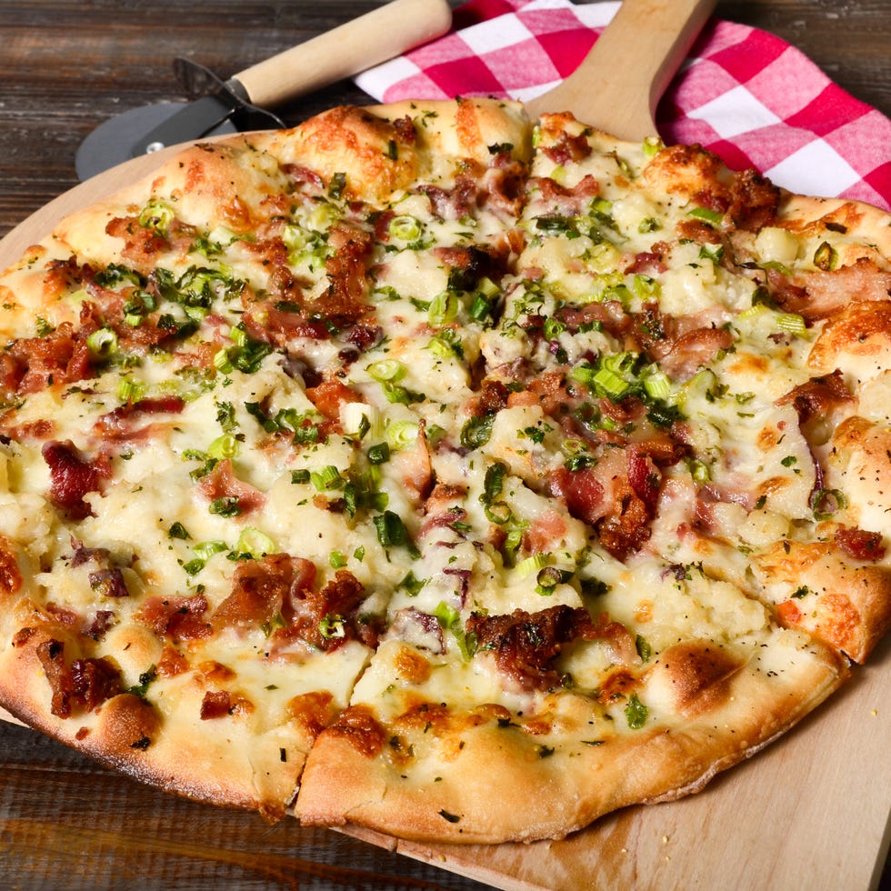 a hearty gourmet pizza with potatoes, bacon, cheese and scallions fresh out of a wood fired oven.