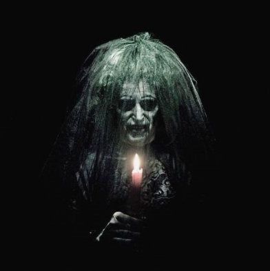 an old woman ghost stands in a dark room in a scene from 'insidious'