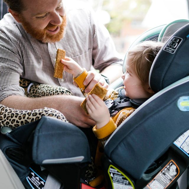 dad strapping child into car seat