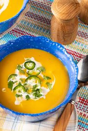 instant pot butternut squash soup with coconut milk cilantro and jalapeno in a blue bowl with salt and pepper shaker