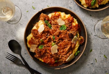 instant pot pork puttanesca with olives, capers, and shaved cheese over polenta