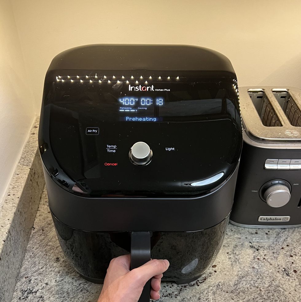 instant pot vortex air fryer set up on countertop with hand for scale