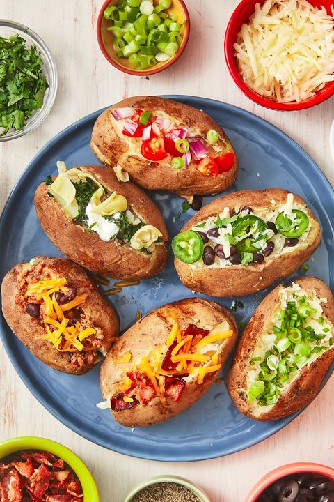 six baked potatoes with different toppings on a blue plate