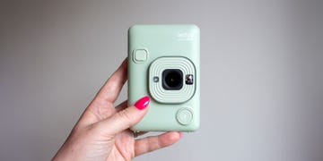 a handheld instant camera in a light green color