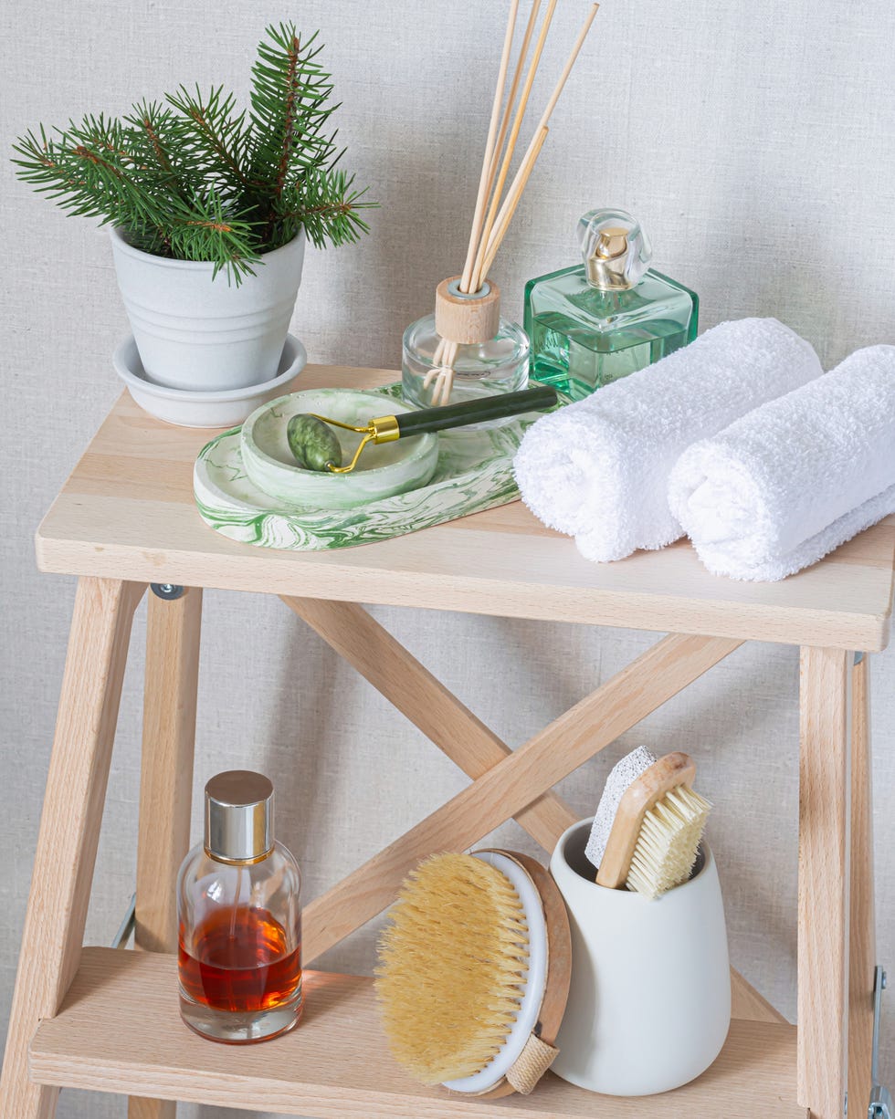 ladder shelf bathroom shot of beauty products, towels, and a plant resting on a ladder shelf in a bathroom