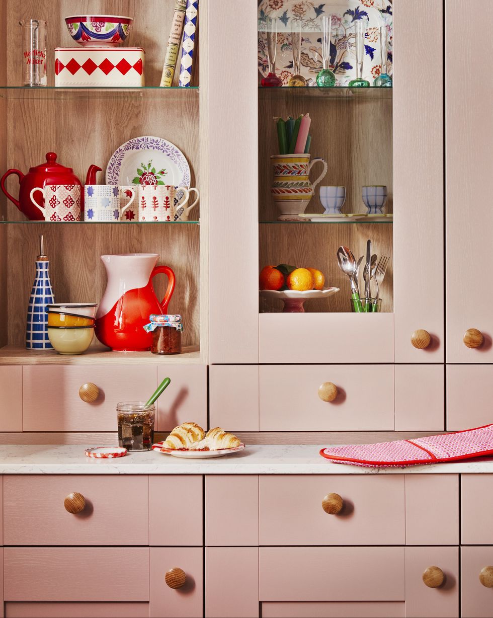 a pink pastel kitchen with wooden handles and glass doors