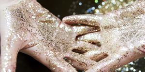 interlocking fingers covered in gold oil and glitter