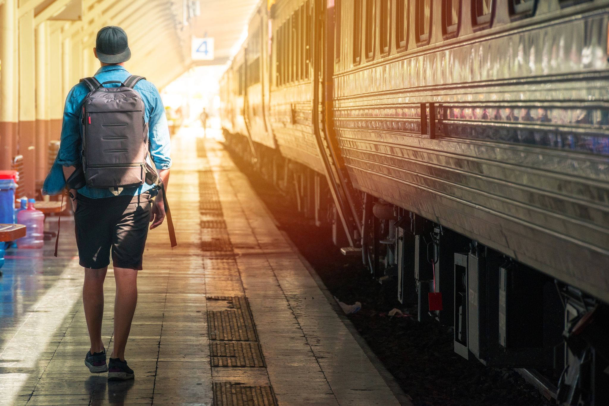 Un uomo con lo zaino in spalla sul binario di una stazione ferroviaria